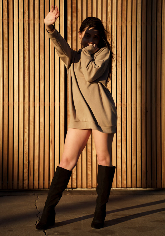 Fashion editorial photo of model in brown jumper and black knww high boots